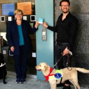 Freude beim Anbringen eines Stickers am Neuen Rathaus: Martina Hellriegel vom Bayerischen Blinden- und Sehbehindertenbund e.V. mit Hund Raven, MdB Anette Kramme, Zweiter Bürgermeister Andreas Zippel und Hund Matou. Bild: Jürgen Lenkeit