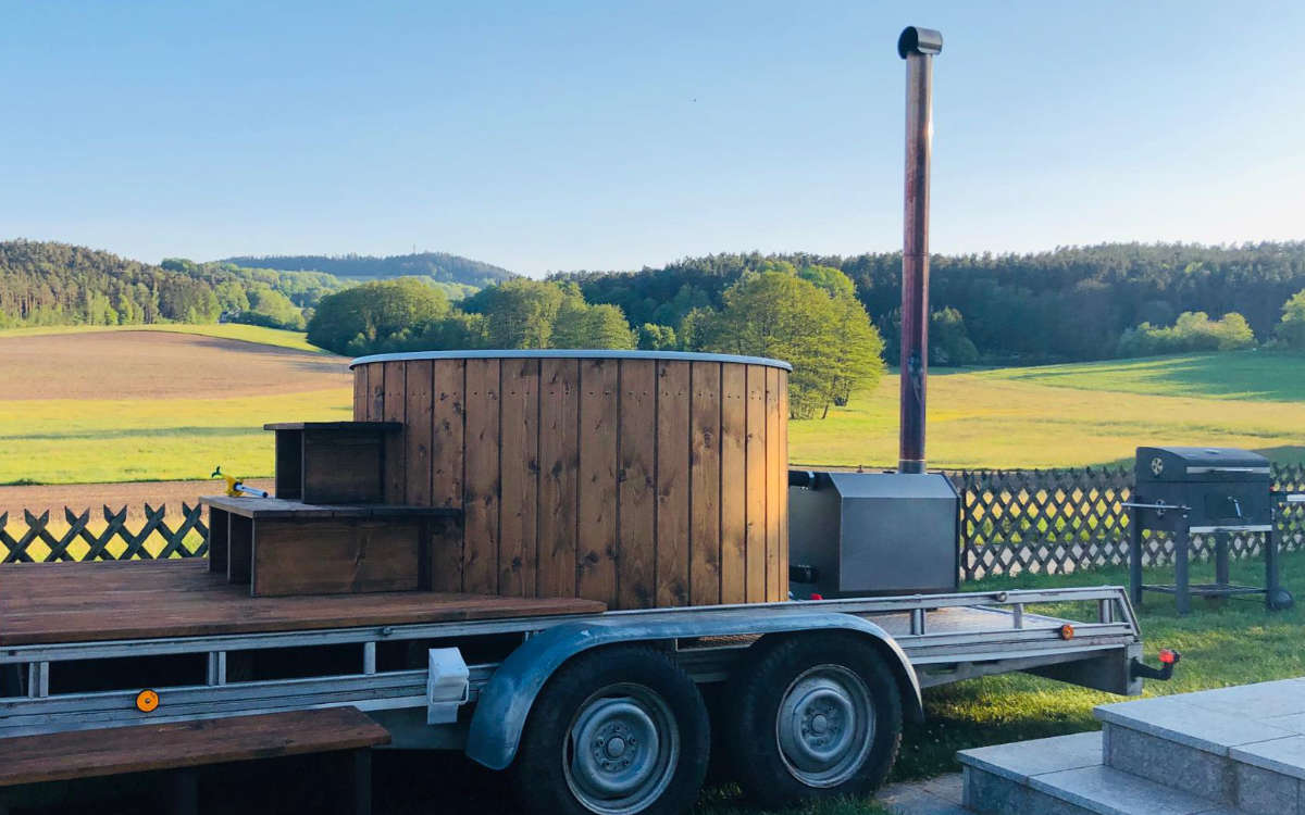 Auch der Zuber kommt auf dem Anhänger daher und wird mit Holzofen betrieben. Praktisch: An der Rückseite ist ein Flaschenhalter. Bild: Saunamichl